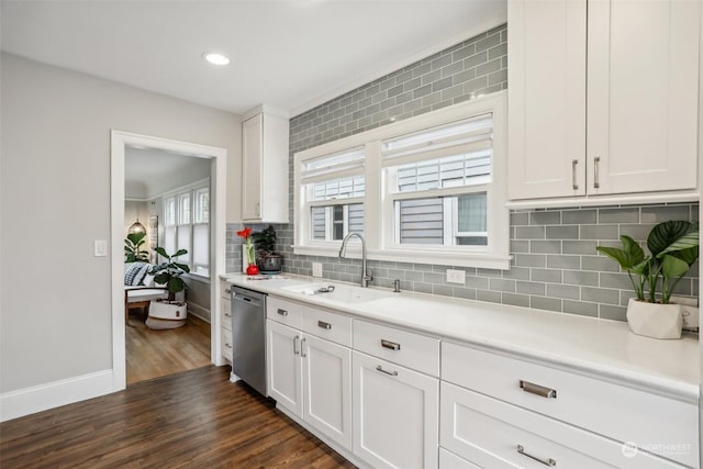 kitchen with sink, white cabinets, stainless steel dishwasher, backsplash, and dark wood-type flooring