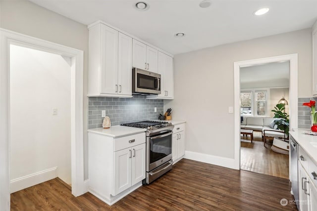 kitchen with appliances with stainless steel finishes, dark hardwood / wood-style floors, tasteful backsplash, and white cabinetry