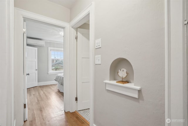 corridor with a wall mounted air conditioner and wood-type flooring