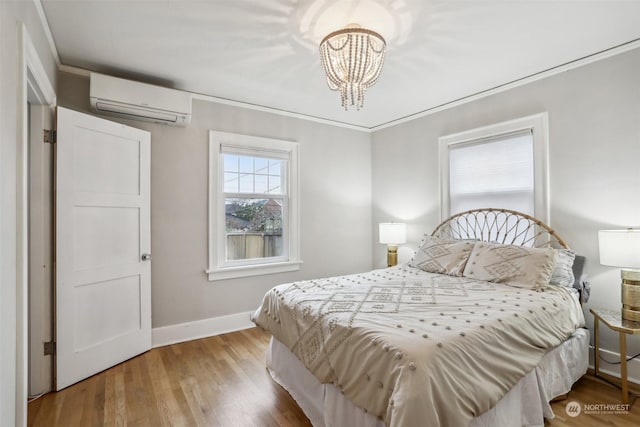 bedroom featuring hardwood / wood-style flooring, ornamental molding, a wall mounted air conditioner, and a chandelier