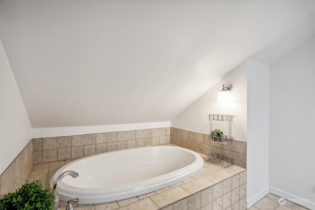 bathroom with a relaxing tiled tub and vaulted ceiling