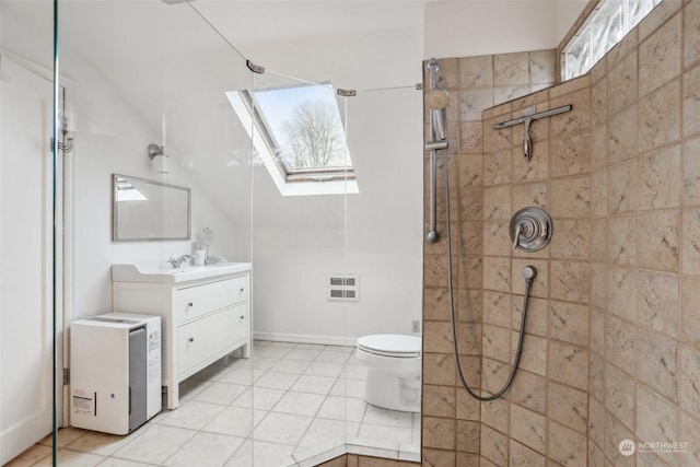 bathroom with a tile shower, a wealth of natural light, vanity, and toilet