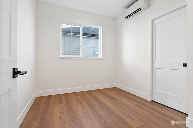 spare room featuring light hardwood / wood-style flooring and an AC wall unit