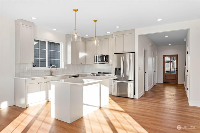 kitchen featuring backsplash, a center island, light hardwood / wood-style flooring, hanging light fixtures, and stainless steel appliances