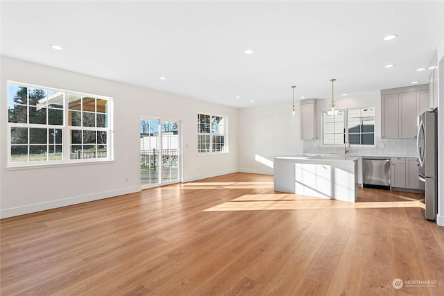 kitchen featuring stainless steel appliances, light hardwood / wood-style flooring, hanging light fixtures, and gray cabinets