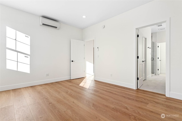 unfurnished bedroom with light hardwood / wood-style flooring and a wall mounted air conditioner