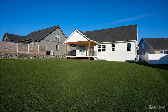 rear view of property featuring a lawn and central AC unit