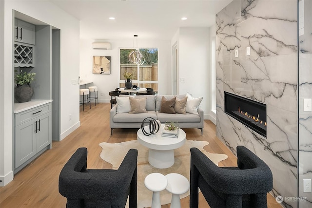 living room featuring light hardwood / wood-style floors, a wall mounted AC, and a fireplace