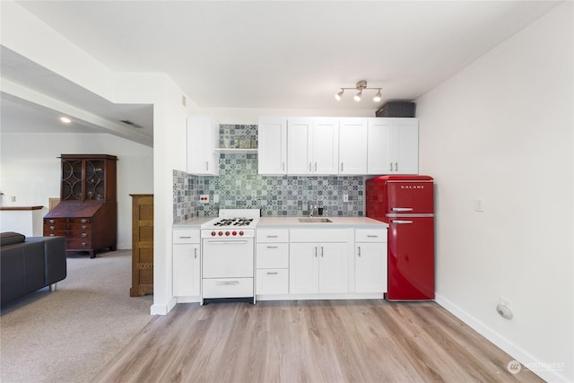 kitchen featuring white cabinets, light wood-type flooring, fridge, and white gas range oven