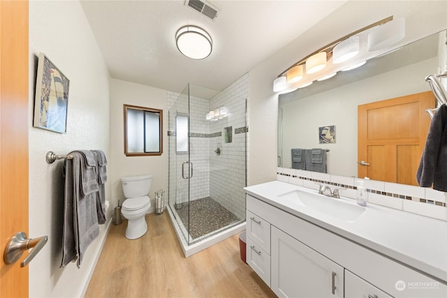 bathroom featuring toilet, vanity, a shower with door, and hardwood / wood-style flooring