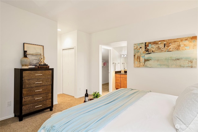 bedroom with ensuite bath, a closet, and light carpet