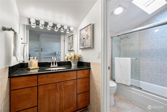 full bathroom with toilet, bath / shower combo with glass door, tile walls, and vaulted ceiling with skylight