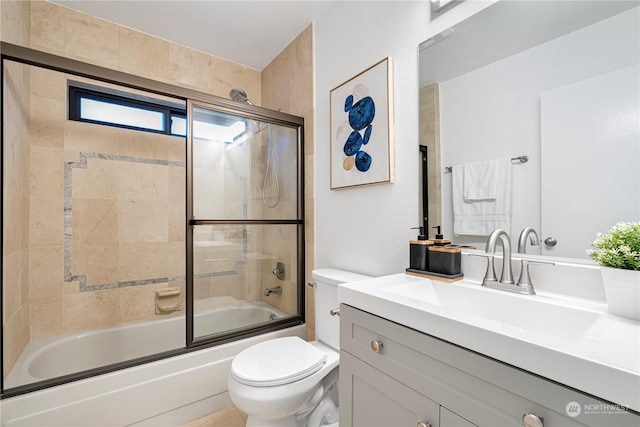 full bathroom featuring toilet, bath / shower combo with glass door, and vanity