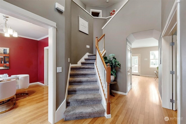 staircase featuring an inviting chandelier, a towering ceiling, and hardwood / wood-style floors