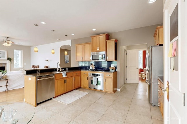 kitchen featuring sink, appliances with stainless steel finishes, kitchen peninsula, pendant lighting, and ceiling fan