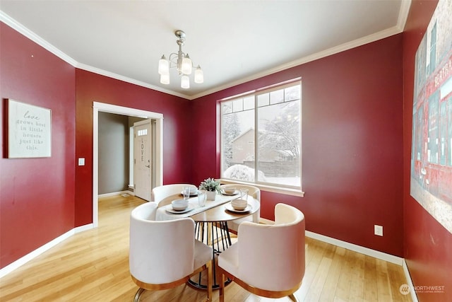 dining space with ornamental molding, hardwood / wood-style floors, and a notable chandelier