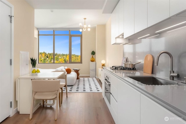 kitchen featuring sink, decorative light fixtures, stainless steel appliances, and white cabinets