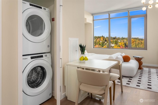 clothes washing area featuring stacked washer and dryer and wood-type flooring