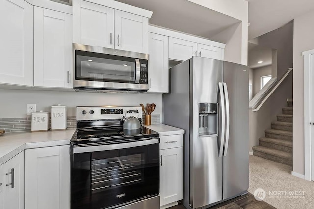 kitchen with dark colored carpet, white cabinets, and appliances with stainless steel finishes