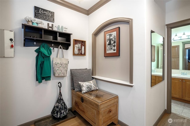 mudroom with sink, light hardwood / wood-style floors, and crown molding