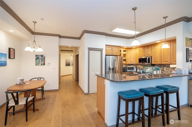 kitchen with a chandelier, dark stone countertops, pendant lighting, and appliances with stainless steel finishes