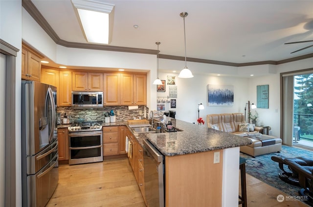 kitchen featuring sink, decorative light fixtures, a kitchen bar, kitchen peninsula, and appliances with stainless steel finishes