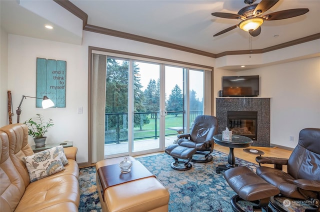 living room with hardwood / wood-style floors, a premium fireplace, ceiling fan, and ornamental molding