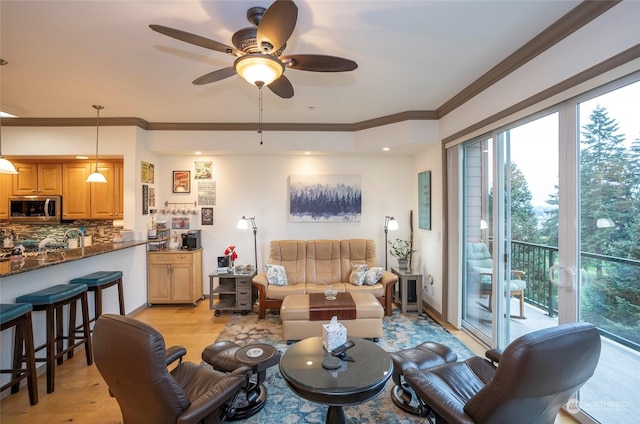 living room featuring ceiling fan, ornamental molding, and light hardwood / wood-style flooring