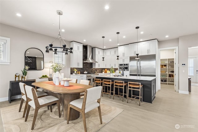 dining space featuring an inviting chandelier, sink, and light hardwood / wood-style floors