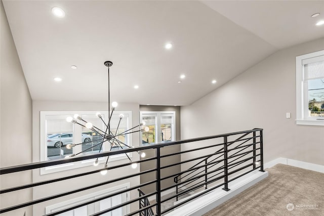 corridor featuring vaulted ceiling, carpet flooring, a wealth of natural light, and an inviting chandelier