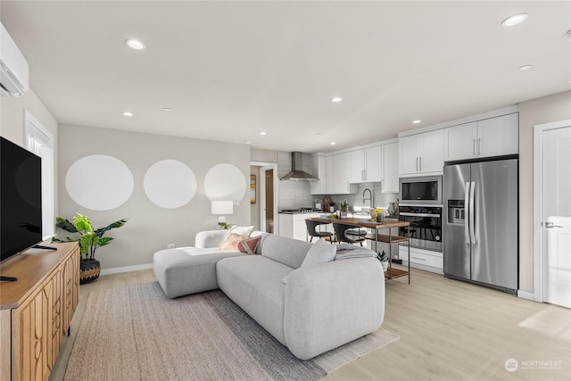 living room featuring sink, light hardwood / wood-style floors, and a wall unit AC