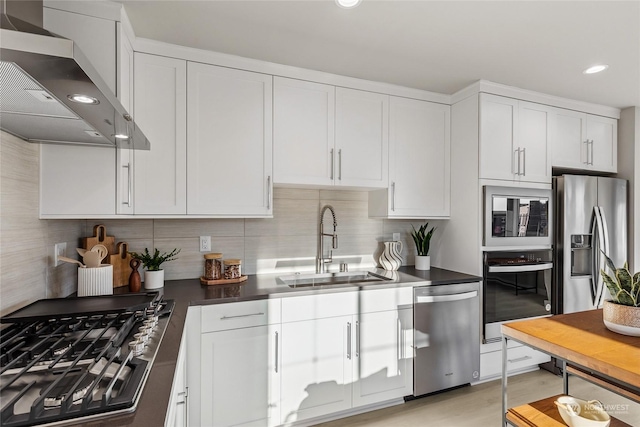 kitchen featuring sink, stainless steel appliances, tasteful backsplash, white cabinets, and wall chimney exhaust hood