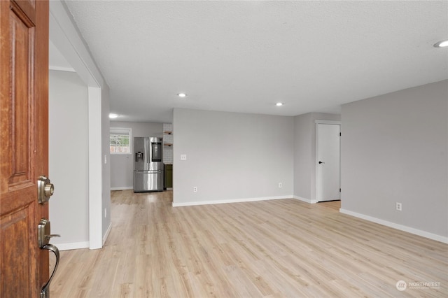 spare room featuring light hardwood / wood-style floors and a textured ceiling