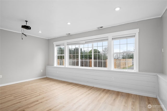 empty room featuring ornamental molding, light hardwood / wood-style floors, and plenty of natural light