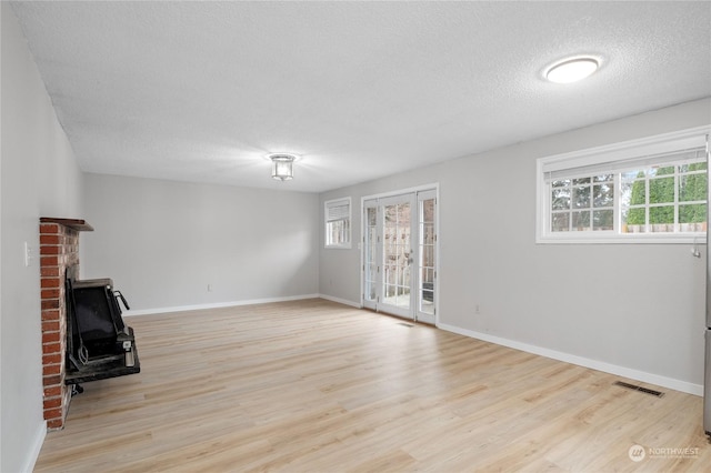 unfurnished living room with a textured ceiling and light hardwood / wood-style floors