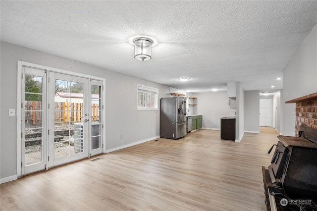 unfurnished living room with a textured ceiling and light hardwood / wood-style flooring