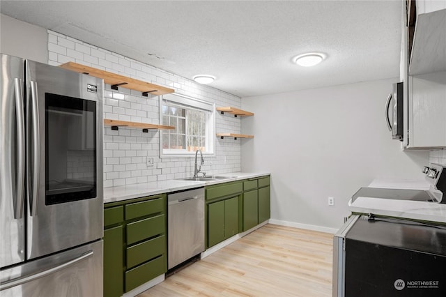 kitchen with stainless steel appliances, light wood-type flooring, green cabinetry, a textured ceiling, and sink