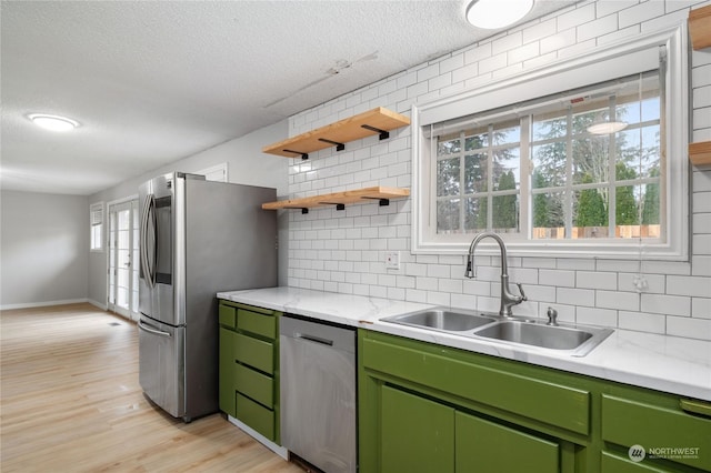 kitchen with tasteful backsplash, sink, stainless steel appliances, and green cabinets