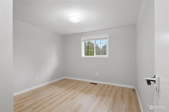 unfurnished room with a textured ceiling and light hardwood / wood-style floors