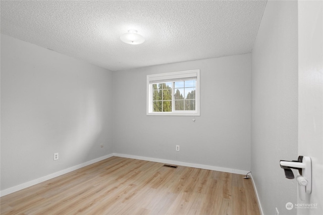 empty room with a textured ceiling and light hardwood / wood-style floors