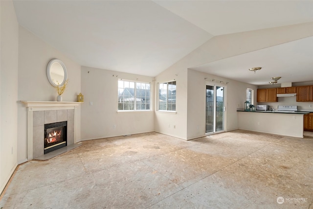 unfurnished living room featuring a tile fireplace and vaulted ceiling