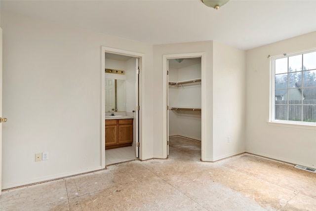 unfurnished bedroom featuring ensuite bathroom, a closet, a spacious closet, and sink