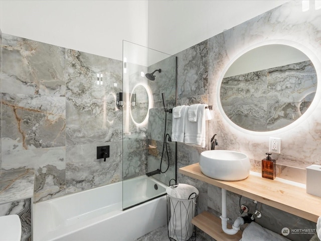 bathroom featuring tile walls, tiled shower / bath combo, backsplash, and sink