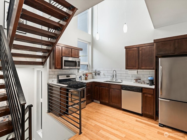 kitchen featuring appliances with stainless steel finishes, decorative light fixtures, backsplash, and sink