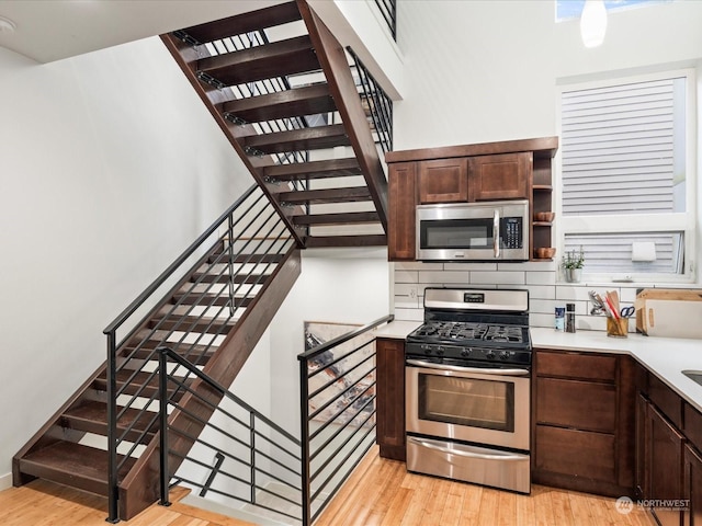 kitchen with light wood-type flooring, dark brown cabinets, and appliances with stainless steel finishes