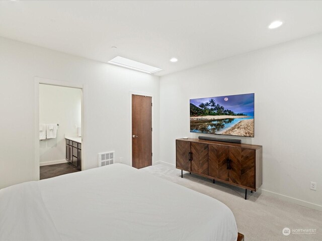 carpeted bedroom with ensuite bath and a skylight