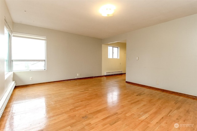 empty room with baseboard heating and light wood-type flooring