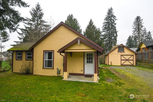 back of house featuring a yard and an outdoor structure