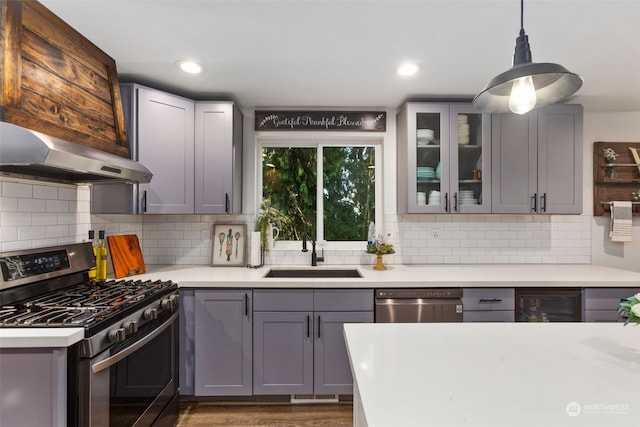 kitchen with decorative light fixtures, stainless steel appliances, backsplash, gray cabinetry, and sink