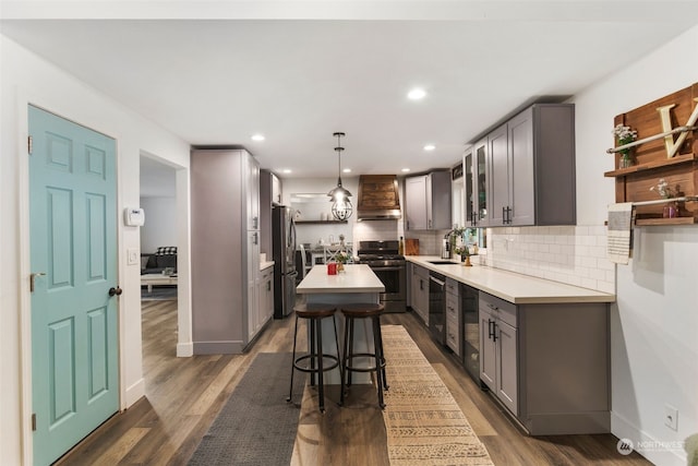 kitchen featuring pendant lighting, a kitchen island, gray cabinetry, a breakfast bar area, and appliances with stainless steel finishes